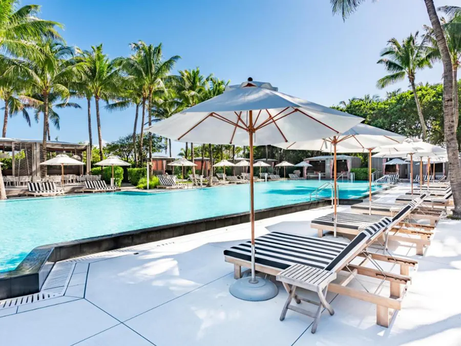 White Monterey umbrellas shading chaise lounges around a resort pool